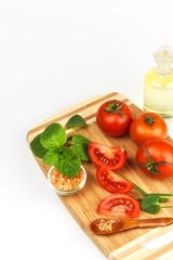 Tomatoes and herbs on a kitchen board. Preparation of healthy food. Raw vegetables. On a white background.