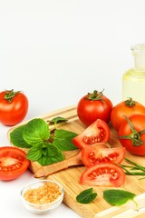 Tomatoes and herbs on a kitchen board. Preparation of healthy food. Raw vegetables. On a white background.