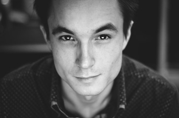 close-up portrait of a young cute guy in a shirt in an office setting, black and white image