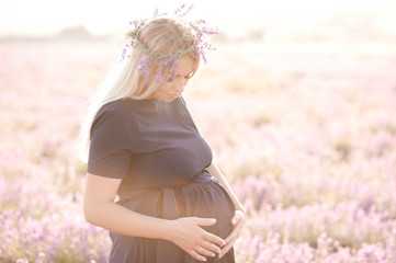 Fototapeta na wymiar Smiling pregnant woman holding tummy posing outdoors. Maternity. 20s.
