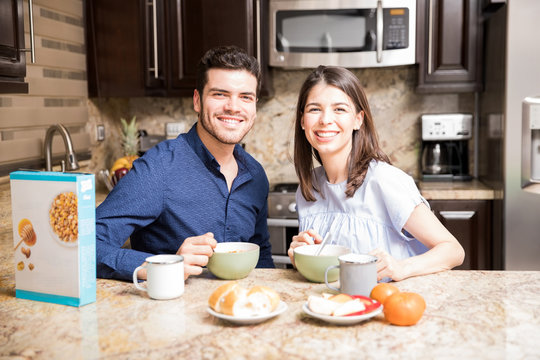 Cheerful couple having breakfast together in kitchen