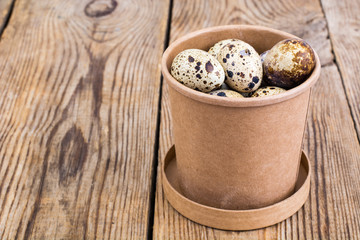 Quail eggs in cardboard box on wooden table