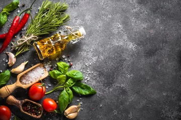 Fotobehang Specerijen, kruiden en olijfolie over zwarte stenen tafel. © nadianb