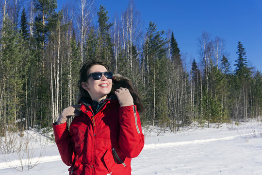 girl in a red jacket walks in the woods and enjoys the spring sun