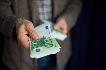 Man in a casual jacket counts and holds hundred 100 euro bills with his hands