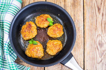 Frying pan with fried cutlets on wooden table