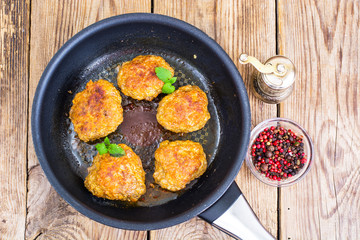 Frying pan with fried cutlets on wooden table