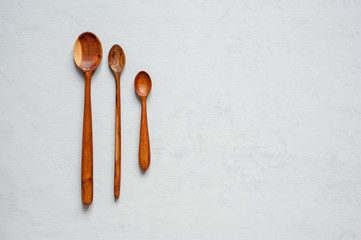 Three wooden spoons of handmade different sizes lie on a light background.