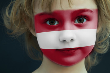 Child with a painted flag of Latvia
