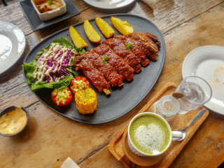 Pork Spare Ribs Barbecue with fried potato and fresh vegetable in black ceramic dish on wooden table