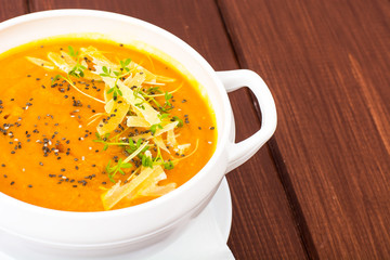 Pumpkin carrot cream soup with parmesan and green shoots of watercress