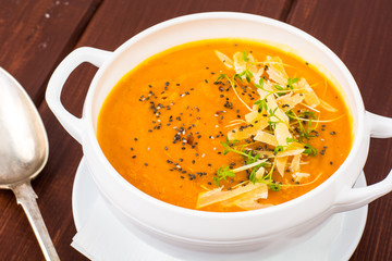 Pumpkin carrot cream soup with parmesan and green shoots of watercress