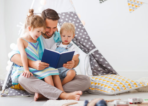 family father reading to children book in tent at home