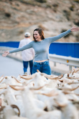 happy young woman playing in front of a group of goats