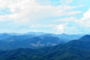 Fototapeta premium Amazing wild nature view of layer of mountain forest landscape with cloudy sky at winter season. Natural green scenery of cloud and mountain slopes background.