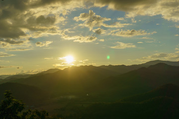 Amazing wild nature view of layer of mountain forest landscape with cloudy sky when sunset or twilight. Natural green scenery of cloud and mountain slopes background. Maehongson,Thailand