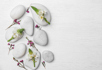 Spa stones and beautiful flowers on wooden background