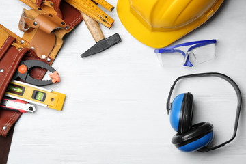 Flat lay composition with headphones, hard hat and tools on table. Hearing protection