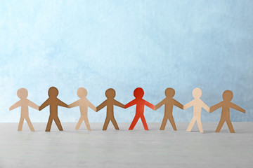 One red paper human among others on table. Difference and uniqueness concept