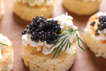 Tasty black caviar appetizer on wooden board