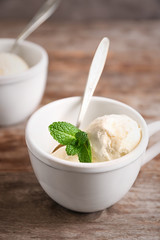 Cup with delicious vanilla ice cream on table