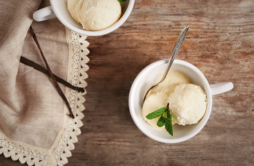 Cups with delicious vanilla ice cream on table