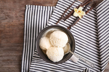 Cup with delicious vanilla ice cream on table