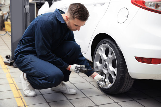 Young mechanic checking tire pressure in service center