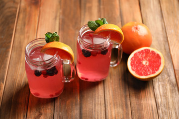 Tasty lemonade with grapefruit and berries in mason jars on table