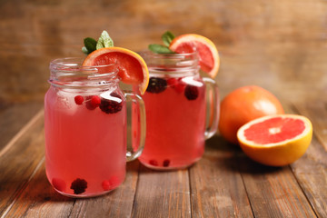 Tasty lemonade with grapefruit and berries in mason jars on table