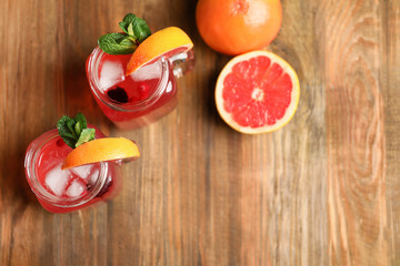 Tasty lemonade with grapefruit and berries in mason jars on table