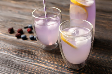 Tasty refreshing lemonade in glassware on table