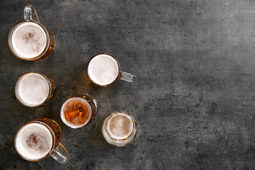 Glassware with fresh beer on grey table, top view