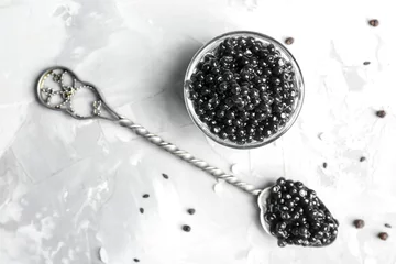  Spoon and bowl with delicious black caviar on grey background © Africa Studio