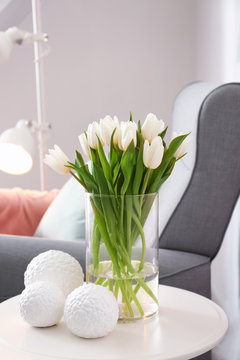 Small table with bouquet of tulips and decor in living room