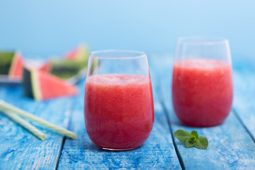 Fresh watermelon smoothie in two glasses on a blue wooden rustic background