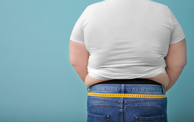 Overweight woman with measuring tape on color background