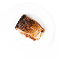 A piece of fried river fish on the plate isolated on white background