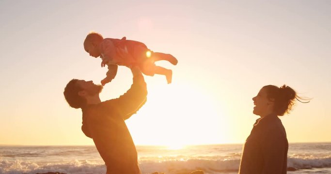 Father and mother playing with their baby boy in the beach 