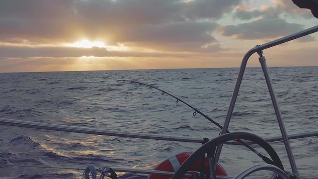 Fish trolling from board of yacht during picturesque sunset in ocean
