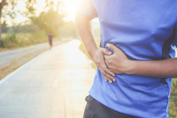 Stomach cramps or Injury while workout concept : Asian man use hands hold on his stomach while...