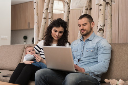 Parents With Baby at Home Using Laptop Computer