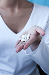 A girl holds on her hand a lot of white tablets