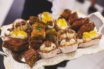 Beautifully decorated catering banquet table with multicolored decorated baked sweet tasty candy dessert assortment variety on kids children party with happy people around