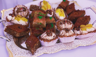 Beautifully decorated catering banquet table with multicolored decorated baked sweet tasty candy dessert assortment variety on kids children party with happy people around