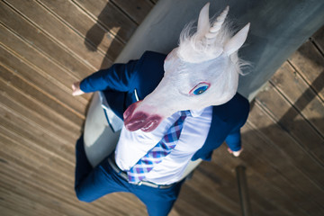 Young man in elegant suit lies under umbrellas on the city waterfront. Unusual businessman in funny...
