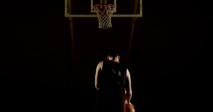 Male basketball player throwing basketball in the basketball hoop 