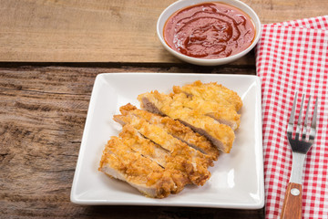 deep fried pork cutlet in a ceramic plate served with ketchup on wooden board. homemade style food concept.
