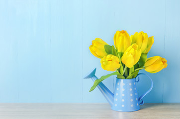 Artificial yellow tulip flowers at blue watering can