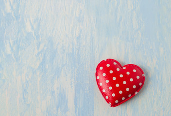 red heart with white polka dot pattern on blue vintage wooden background
